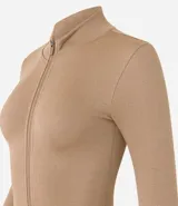 Campera deportiva color beige, de corte ajustado, confeccionada en tejido de poliamida seamless con textura acanalada y cuello alto. Posee cierre delantero por cremallera y mangas largas.