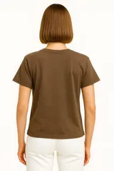 Remera celeste de manga corta y cuello redondo, con estampado de sardinas sobre fondo a cuadros rojos y blancos. Incluye texto con los nombres de las ciudades de Cagliari y Sardina.