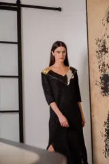 Vestido negro de noche con mangas 3/4, cuello en V con detalles de cuero entrelazado, terminación en flecos y tajos laterales.