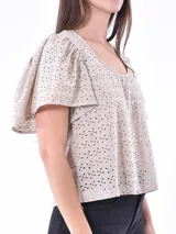 Blusa color blanco con mangas cortas abullonadas y calado con pequeños orificios.