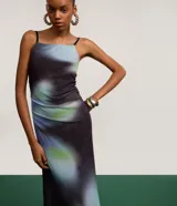 Vestido largo de tirantes finos, con escote recto y detalle fruncido lateral. Presenta un estampado abstracto con manchas difuminadas en tonos azul, verde y negro.
