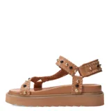 Sandalias bajas color tostado, con plataforma y tiras de cuero sintético con tachas doradas y negras.