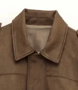 Chaqueta tipo bomber de gamuza color marrón, con cuello camisero, calce suelto y mangas amplias.