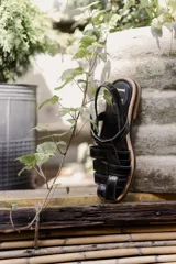 Sandalias de cuero marrón con tiras entrecruzadas y hebilla dorada al tobillo.