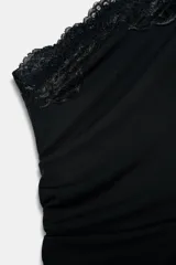 Vestido negro de escote asimétrico con un solo hombro y manga larga ancha. Presenta detalles de encaje negro en el escote, el ruedo asimétrico y un corte 'cut out' en el lateral del torso.