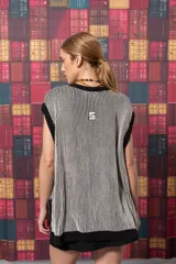 Chaleco largo de punto con rayas verticales en tonos beige y negro. Tiene cuello redondo, sisas amplias con ribete negro y aberturas laterales en el ruedo.