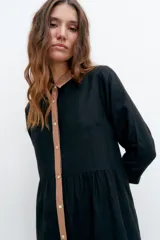 Vestido corto negro con cuello camisero y botones frontales color beige.