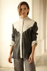Camisa de cuero color negro y beige con corte a la cadera, cuello mao, cierre frontal con botones y detalle de tachas metálicas en el canesú.