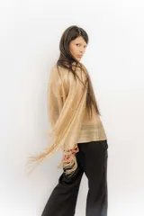 Poncho tejido color cobre con apliques de piedras y flecos.