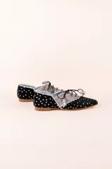 Zapato blucher de terciopelo negro con estampado de estrellas plateadas, puntera plateada brillante y cordones negros. Interior de cuero y suela de cuero.