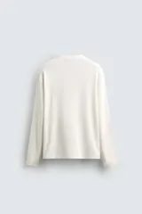 Camiseta color crudo de manga larga, corte relaxed fit y cuello redondo combinado con cierre frontal de botonadura.