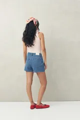 Short pollera de denim azul con corte asimétrico y cierre con botón.