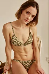 Conjunto de bikini blanco con textura, compuesto por un corpiño de triángulo fijo con breteles regulables y almohadillas desmontables, y una bombacha vedetina con frunce elástico en los costados.