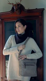Bandolera beige de símil cuero con dos bolsillos frontales con cierre, un bolsillo trasero, tres bolsillos internos y correa larga regulable.