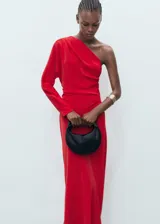 Vestido largo de fiesta color rojo, con escote asimétrico de un solo hombro y manga larga abullonada. Corte ajustado en la cintura y falda recta con abertura lateral.