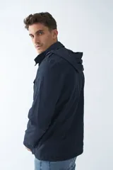 Campera de gabardina azul marino con capucha desmontable y ajustable, bolsillos tipo cartera y cierre frontal con botones.