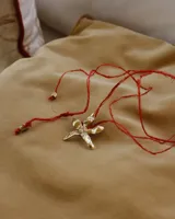 Collar artesanal con dije de flor plateada, realizado con hilo de seda natural teñido a mano.