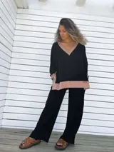 Conjunto de buzo y pantalón negro con detalles en color beige. El buzo es de corte holgado, con cuello en V y puños con ribete. El pantalón es de corte recto y tiro alto.