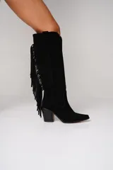 Bota texana de cuero color negro, con caña alta, punta fina, taco de 10cm y detalle de flecos en el lateral externo.