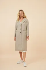 Tapado largo color beige con cuello solapa y corte recto. Cierre frontal con botones, detalles aplicados en la parte delantera, tajo en la espalda y bolsillos ojal con tapa. Con forro. Hecho en Uruguay con tela 100% lana fina sin teñir.