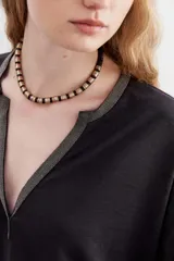 Gargantilla con lentejuelas metálicas en tonos negro, dorado y plateado.
