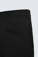 Pantalón negro de algodón con corte relajado y pierna ancha (flare fit). Presenta cierre frontal con botón y cremallera, bolsillos delanteros y bolsillos traseros de plastrón.