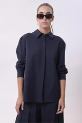 Camisa blanca de corte oversize, con cuello clásico y mangas largas con puños abotonados.