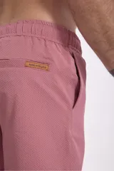 Short de baño color verde oliva con textura de rayas finas en relieve y cordón de ajuste blanco en la cintura.