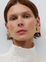 Pendientes de cubo aplastado en color dorado, con cierre de broche y diseño elegante.