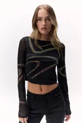 Top negro con aplicación de brillos en diseño ondulado y mangas transparentes.