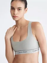 Corpiño deportivo Calvin Klein color gris, sin relleno, con escote en U, espalda cruzada y banda elástica con logo.