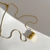 Collar dorado con cadena de eslabones y dije rectangular con textura y cristales incrustados.