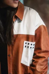 Camisa de cuero color naranja con bolsillo delantero, canesú con detalles en tiento y corte oversize.