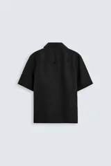 Camisa color marrón oscuro de corte relaxed fit, confeccionada en tejido de lino. Tiene cuello bowling, manga corta, bajo con aberturas laterales y cierre frontal de botonadura.