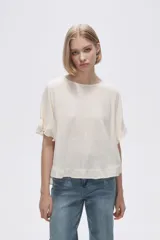 Blusa color marfil de corte holgado, con cuello redondo y mangas cortas con volados.