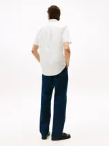 Camisa blanca de corte regular, confeccionada en algodón Oxford con cuello abotonado, manga corta y logo de Tommy Hilfiger bordado en el pecho.