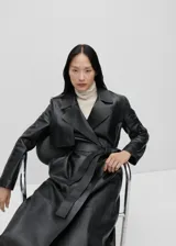 Abrigo midi negro de piel ovina, con cuello de solapa, diseño cruzado, trabillas y cinturón en la cintura.