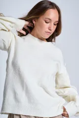 Sweater color crema de hilado frizado con cuello redondo y mangas largas. Presenta apliques de flores en los hombros y mangas.