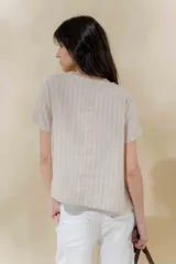 Blusa de lino color beige con rayas verticales negras, corte recto, escote redondo y mangas cortas.