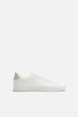 Zapatillas blancas de cuero sintético, con cordones y suela plana.