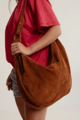 Cartera hobo grande de cuero descarne color marrón, con correa de hombro ajustable y cierre superior con cremallera.