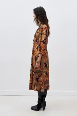 Vestido midi con estampado de mariposas en tonos naranja, verde y negro. Tiene escote en V, mangas largas abullonadas y abertura lateral en la falda.
