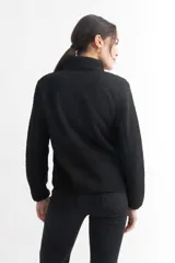 Campera negra de corderito con cierre frontal y cuello alto. Tiene un bolsillo con cierre en el pecho y bolsillos laterales.