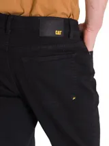 Pantalón de jean de calce slim, color celeste claro, con cinco bolsillos y logo CAT en la parte trasera.