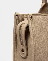 Bolso tipo shopper en efecto cuero graneado, color beige, con asas largas y detalles de cierre frontal.