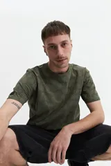 Remera blanca con estampado abstracto en tonos grises, de manga corta, corte regular y cuello redondo.