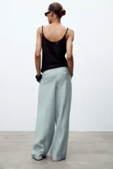 Pantalón de tiro medio color celeste confeccionado en hilatura con mezcla de lyocell. Tiene bolsillos laterales, pinzas delanteras, pierna ancha y cierre frontal con cremallera y botón.