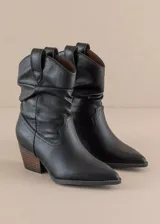 Botas texanas negras de cuero sintético, con caña baja arrugada, puntera fina y taco de madera. Diseño clásico con detalles de costuras y tiradores laterales.