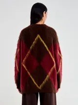 Cardigan largo de punto mohair con diseño de rombos en tonos marrón, bordó y amarillo. Presenta escote en V, cierre frontal con botones al tono y un calce holgado.