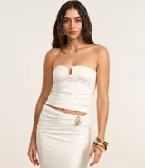 Blusa sin breteles confeccionada en jersey color blanco, con detalle de adorno en forma de U en el busto y fruncidos laterales.